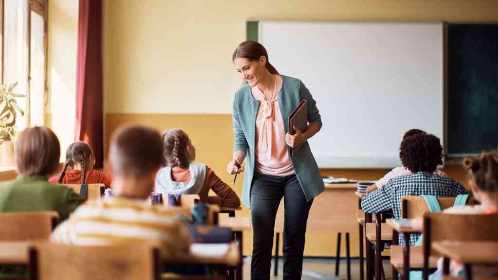 nauczycielka podchodzi do uczniów co pokazuje jak uczyć dzieci