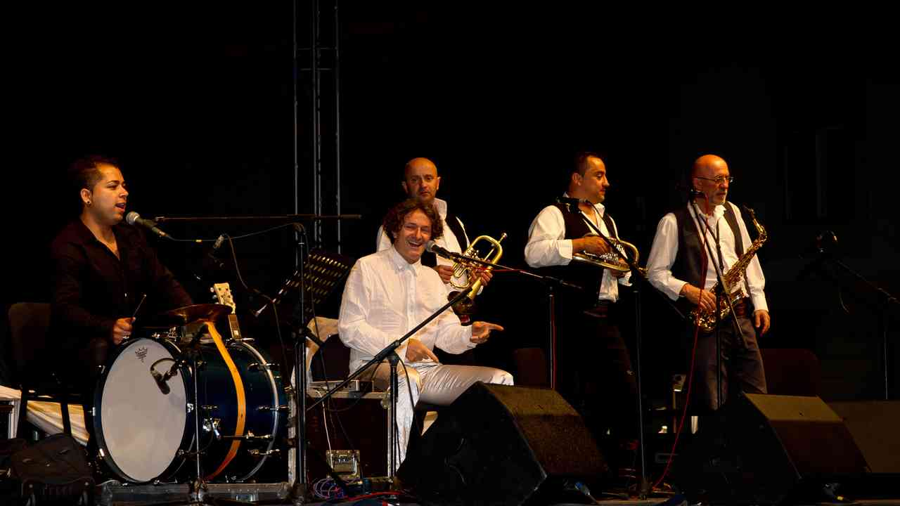 Goran Bregović podczas koncertu z zespołem. Muzyk związany z Bijelo Dugme, którego biografia sięga czasów komunistycznej Jugosławii.
