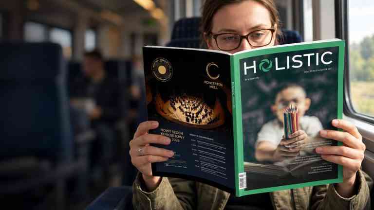 Kobieta czyta kwartalnik Holistic News w pociągu. Na okładce najnowszego numeru temat szkoły, AI w edukacji i współczesnych wyzwań społecznych.